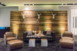 Cohiba - Pouf - Aluminium & Cuir brun utilisé dans le cadre de la réalisation Mur Bois Lounge